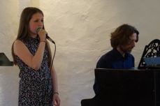 Marta Vevatne sang seg inn i alles hjerter under medarbeiderfesten. Ved pianoet sitter Marius Astrup Thoresen.