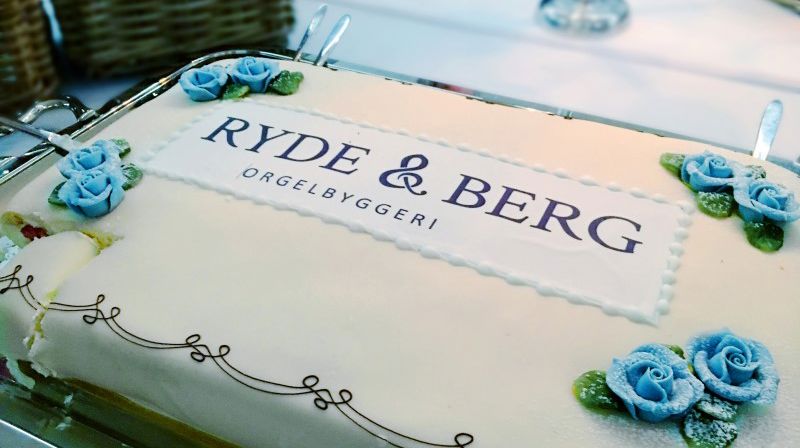 Bløtkake pyntet med roser og logoen til orgelbyggeriet Ryde & Berg.