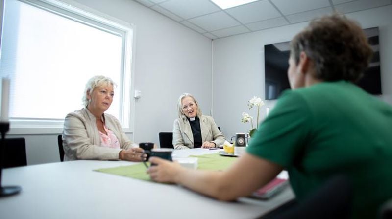 Tre personer rundt et bord der de diskuterer