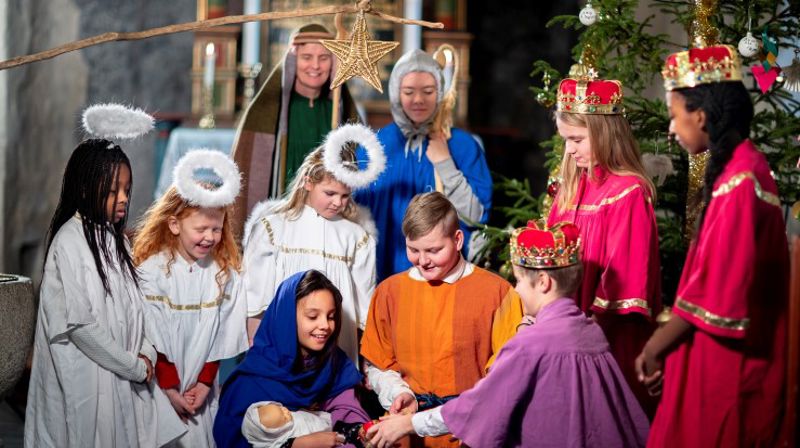 Levende julekrybbe spilt av barn. Josef og Maria holder Jesus. Rundt står engler og gjetere. 