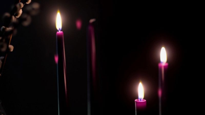 En adventsstake der tre av fire lys er tent. Julen nærmer seg i kirken.