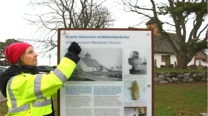 Arkeolog Jone Kile-Vesik monterer nytt informasjonsskilt ved Gamle Glemmen kirke i Fredrikstad, foto: Silje Haugsten Ellefsen
