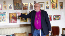 Biskopen foran ikonsamlingen sin hjemme i stua.