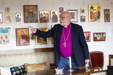 Biskopen foran ikonsamlingen sin hjemme i stua.