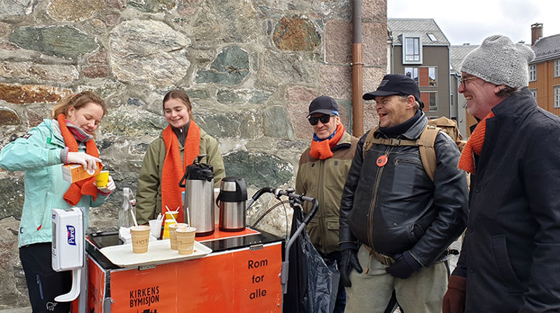 Kirkens bymisjon på plass med kaffevogna utenfor Vår Frue kirke. Til venstre på bildet er Ingrid Bøe og Julie Sandvik, to studenter i Trondheim som har meldt seg som frivillig til å servere kaffe. (Foto: Herborg Finnset)