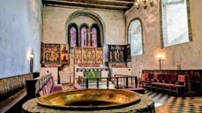 Trondenes kirke i Harstad var blant mottakerne av tilskudd i forrige runde. Her er kirkens altertavle, med romansk døpefont i forgrunnen. Foto: Den norske kirke.