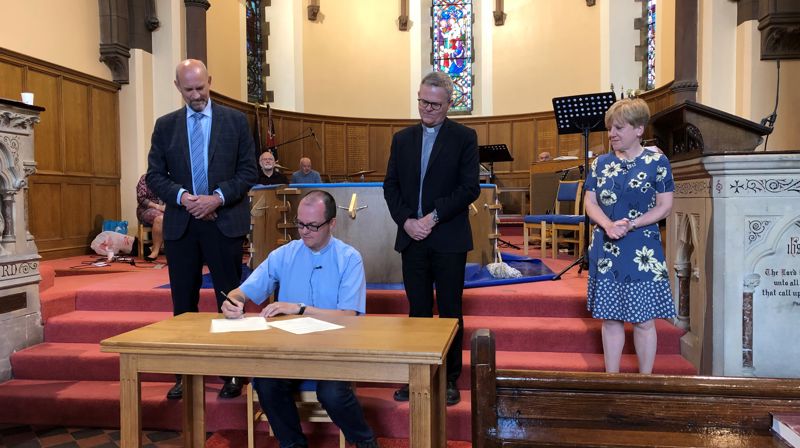 Simon Bickersteth, presten i St. James, signerer vennskapsavtalen. Sokneprest Morten Sandland og menighetsrådsleder Svein Ragnvald Tjora står bak.