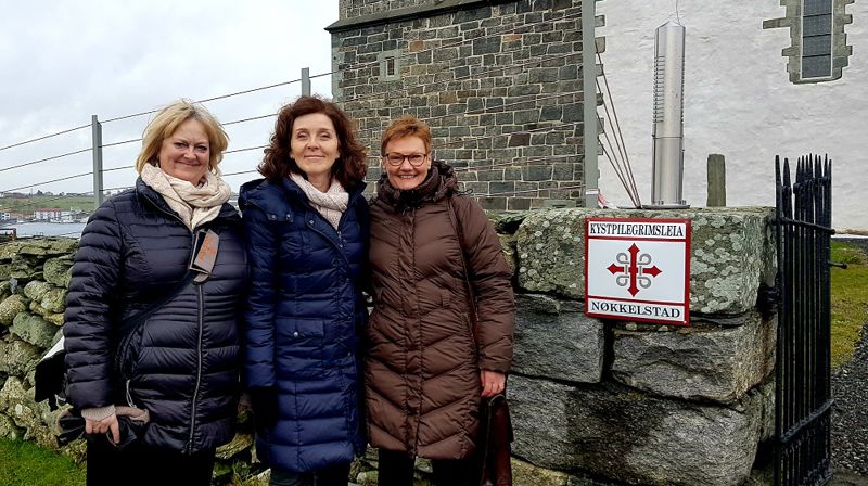 Kulturrådgiver Ragnhild Halle, Krf-politiker Gunn-Marit Lygre og prosjektkoordinator Wenche Lindtner foran Avaldsnes kirke, nå et Nøkkelsted langs Kystpilegrimsleia til Nidaros.