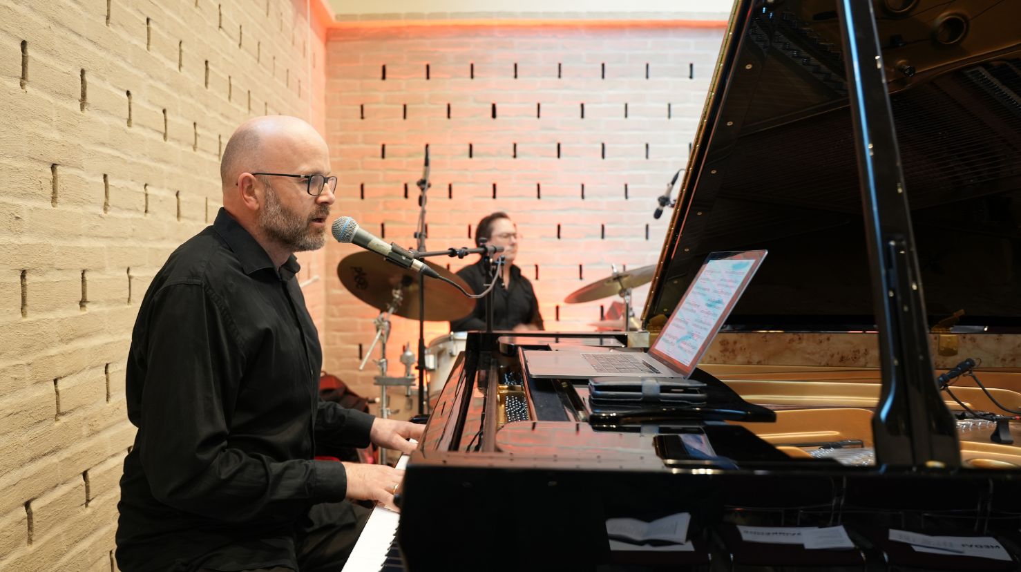 Mannlig pianist og trommis i moderne kirke. Foto.