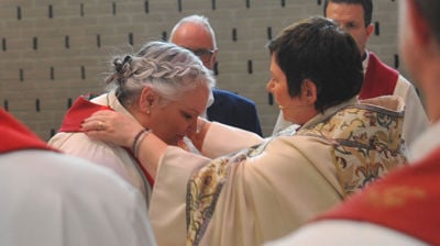 Biskopen legger en stola over skuldrene til den nye kapellanen i Søreide, Gunn Austad. Den er et tegn på at man har en vigslet tjeneste i kirken. Foto: Jens Z. Meyer