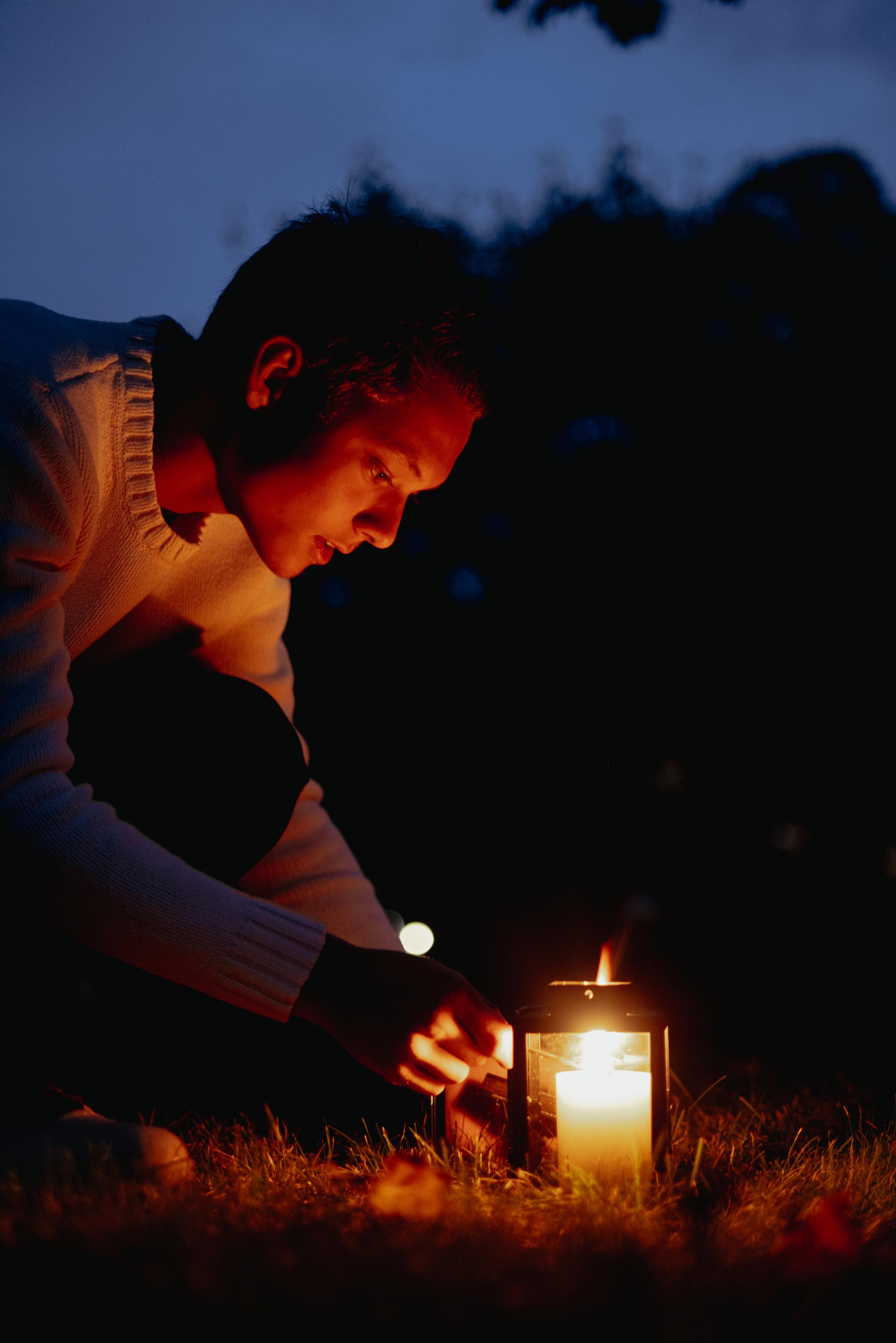 Ung person tenner lys på graven