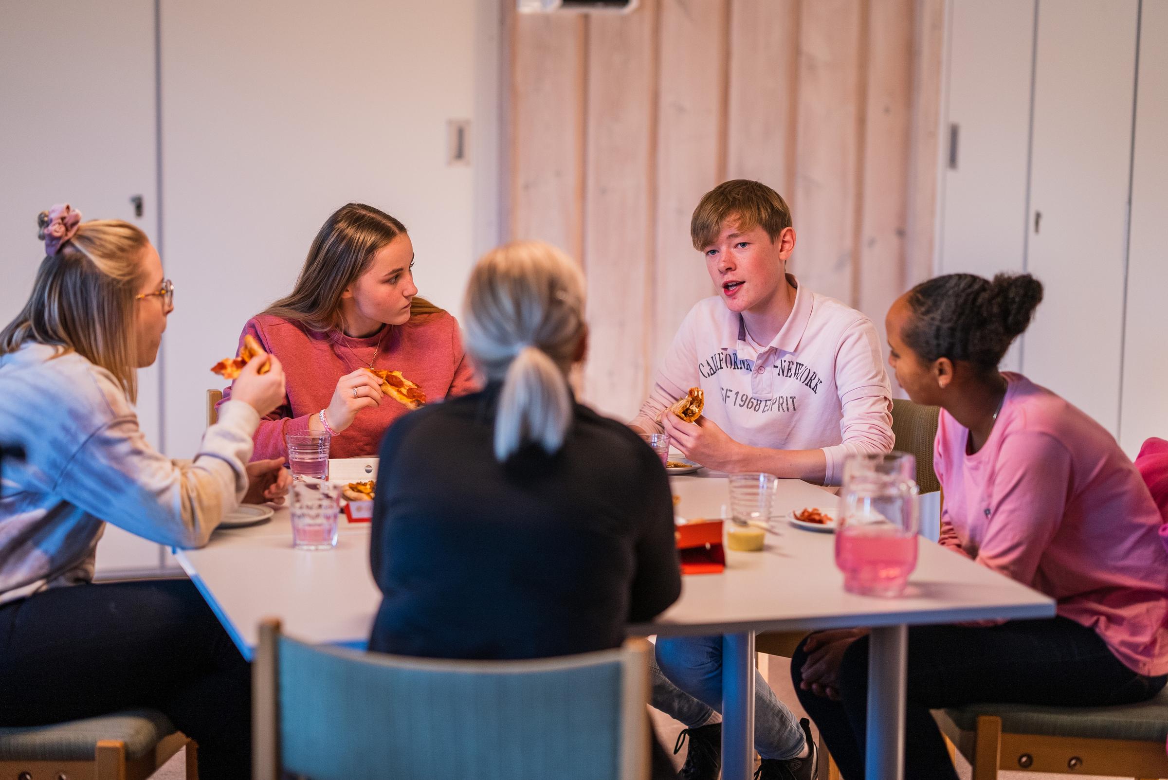 Ungdommer spiser og snakker rundt et bord