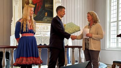 Jens Rikheim får gåve av soknerådsleiar Anne Karin Brugrand, Nora Henriette Grønvold Eriksen er òg tilstades på bilde. 