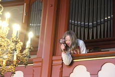 Bilde av en jente på orgelgalleriet i kirka. Hun kikker gjennom et forstørrelsesglass.