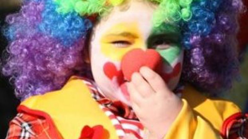 Bilde av et barn ukledd som klovn med fargerik parykk.