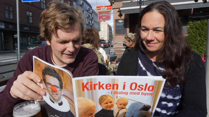 Anne og Lars koser seg i vårsola med fellesrådets Årsmagasin, "Kirken i Oslo - i dialog med byen".