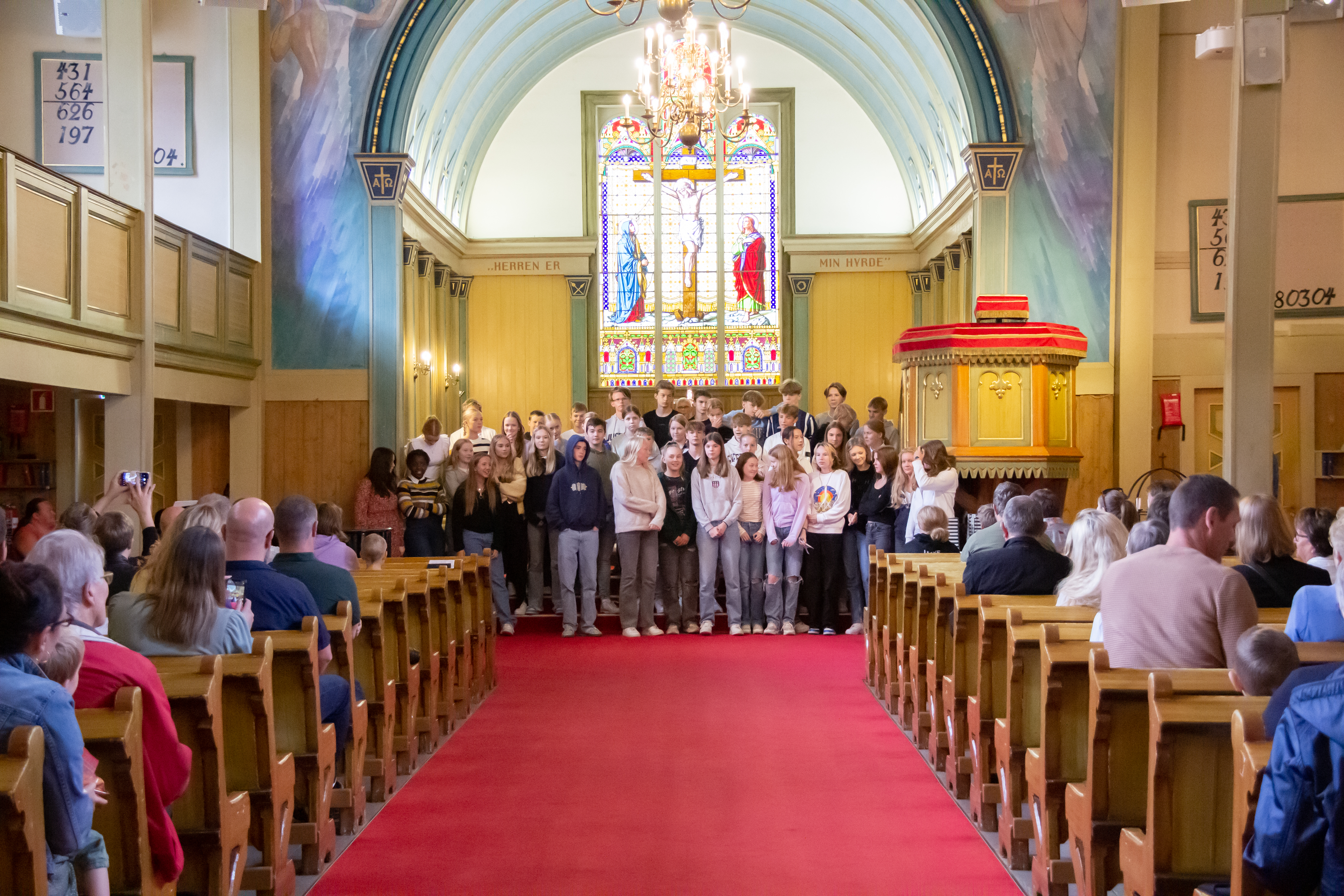 Ungdommer står samlet i kirketrappen, menigheten sitter i benkene