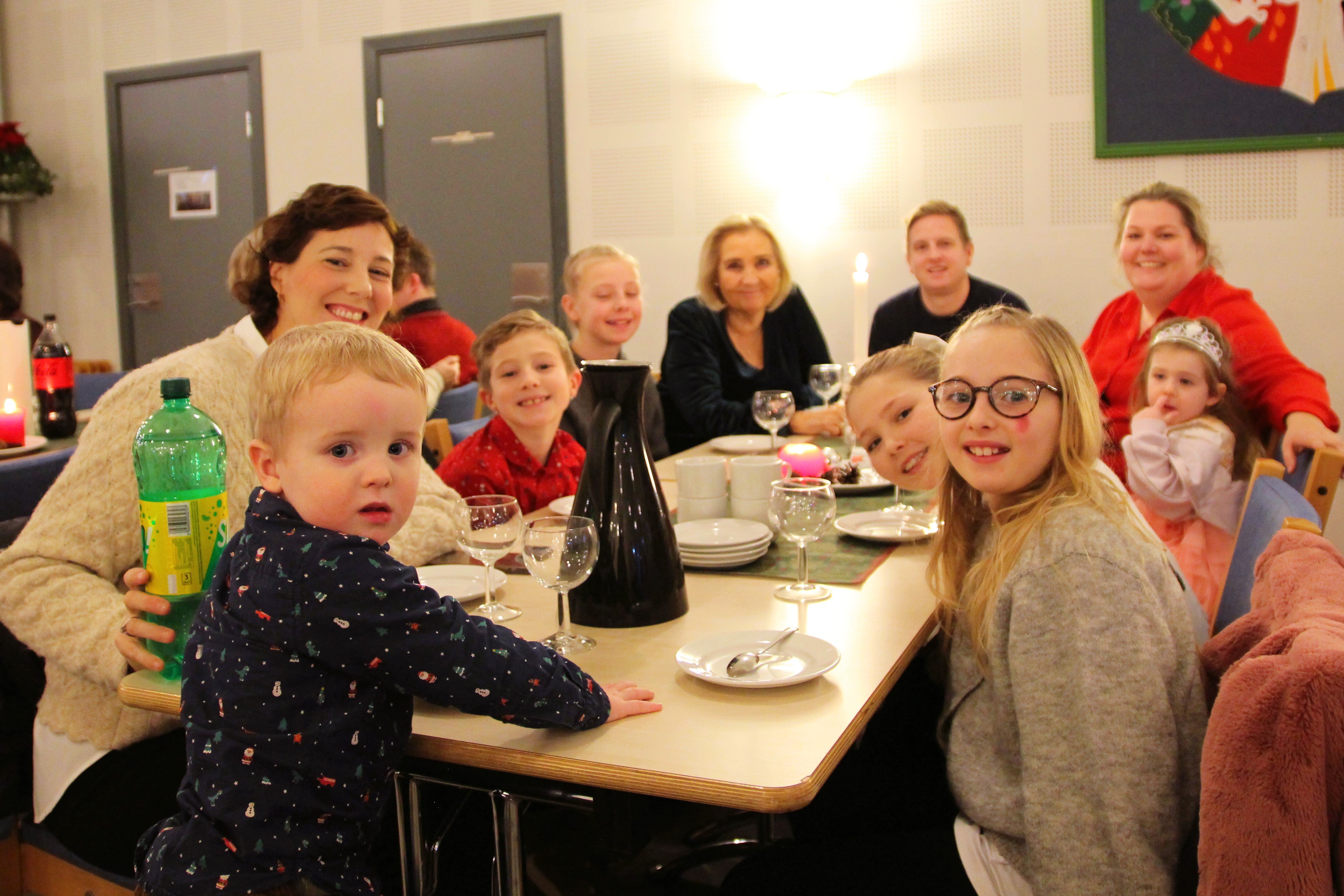 Fornøyd familie ed flere barn smiler rundt et bord