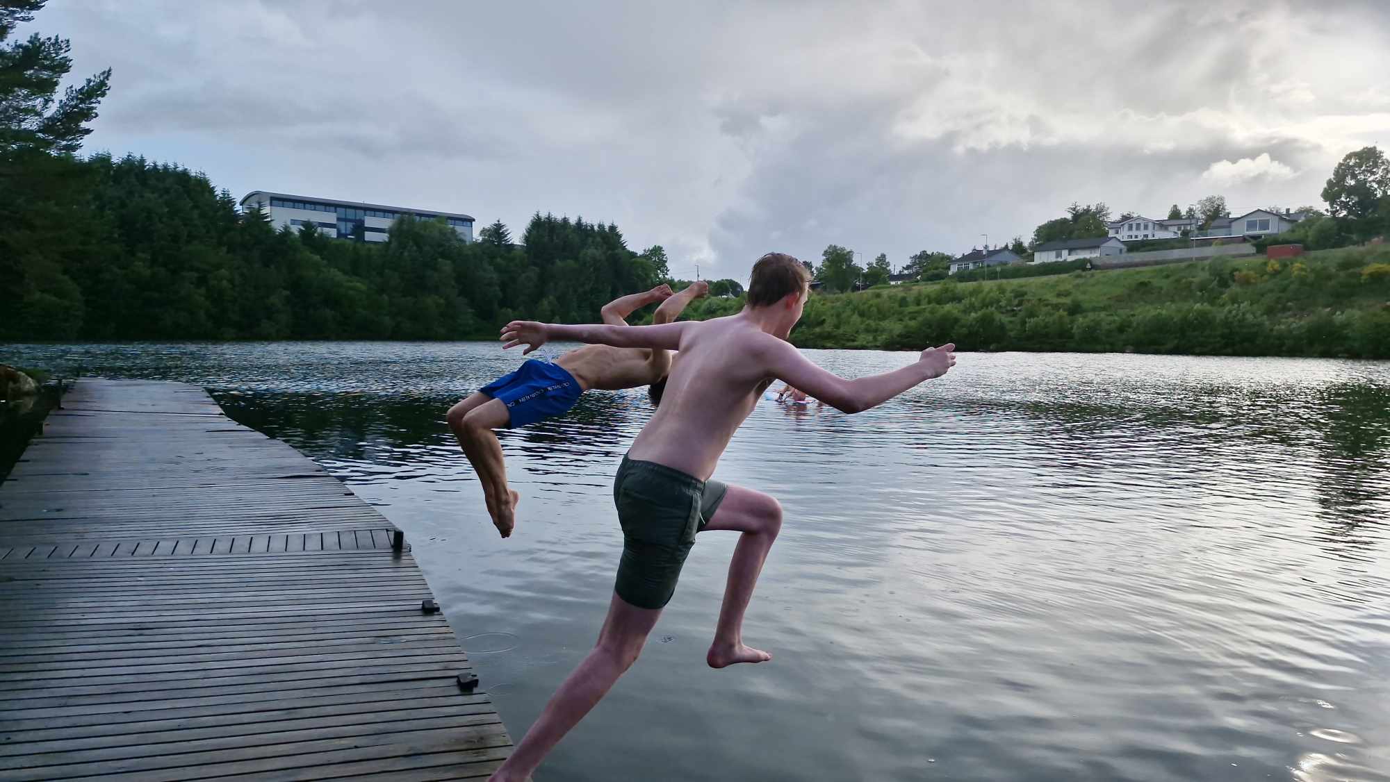 To ungdommar hoppar ut i vatnet! Ein av dei tek baklengs salto.