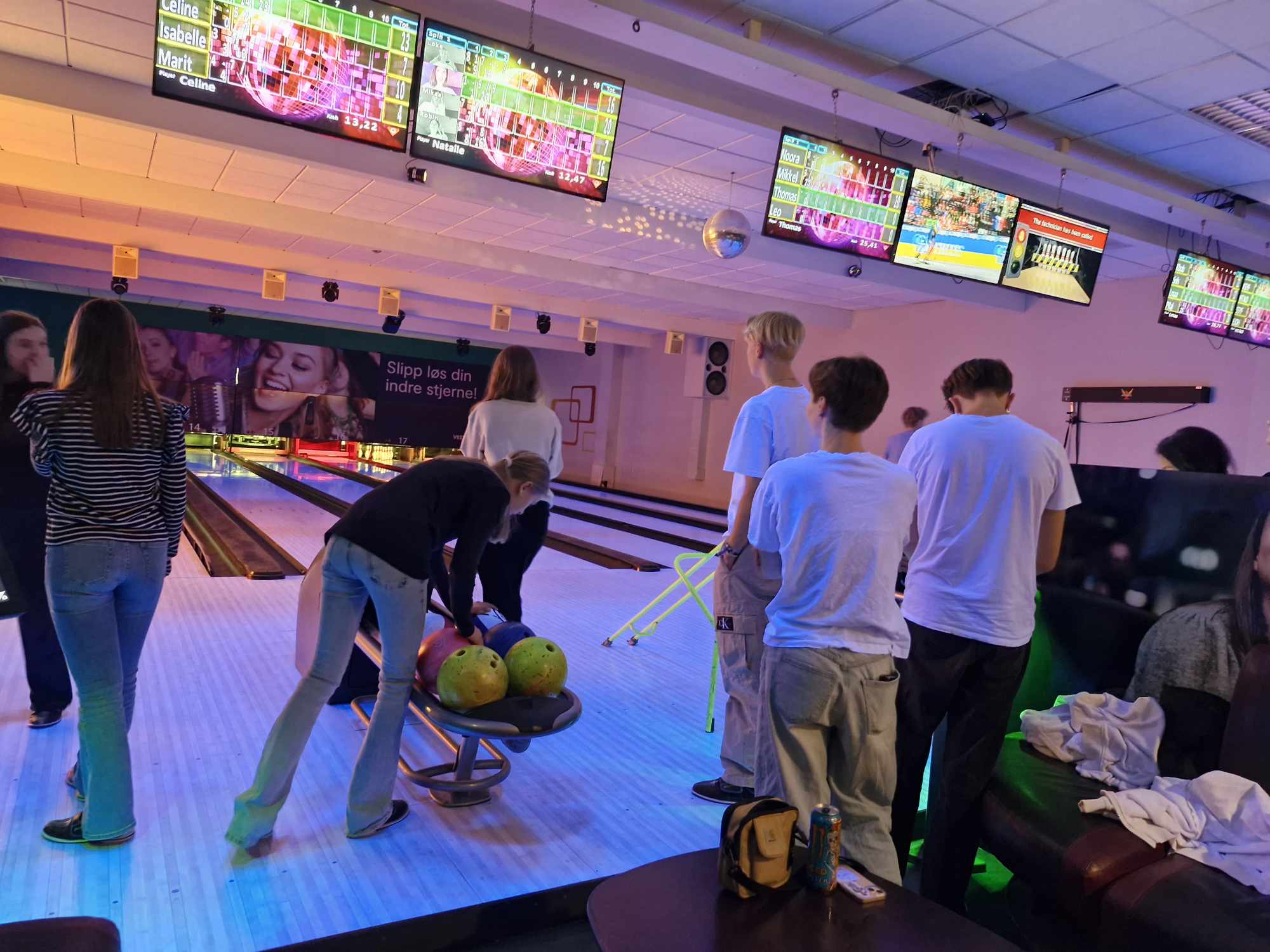 Ungdommar speler bowling, nokon bøyer seg ned for å plukke opp bowlingkule
