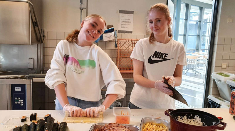 To jenter står på et kjøkken og lager mat