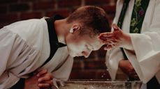 Ung mann døpes i hvit kappe i DNK. Foto Malin