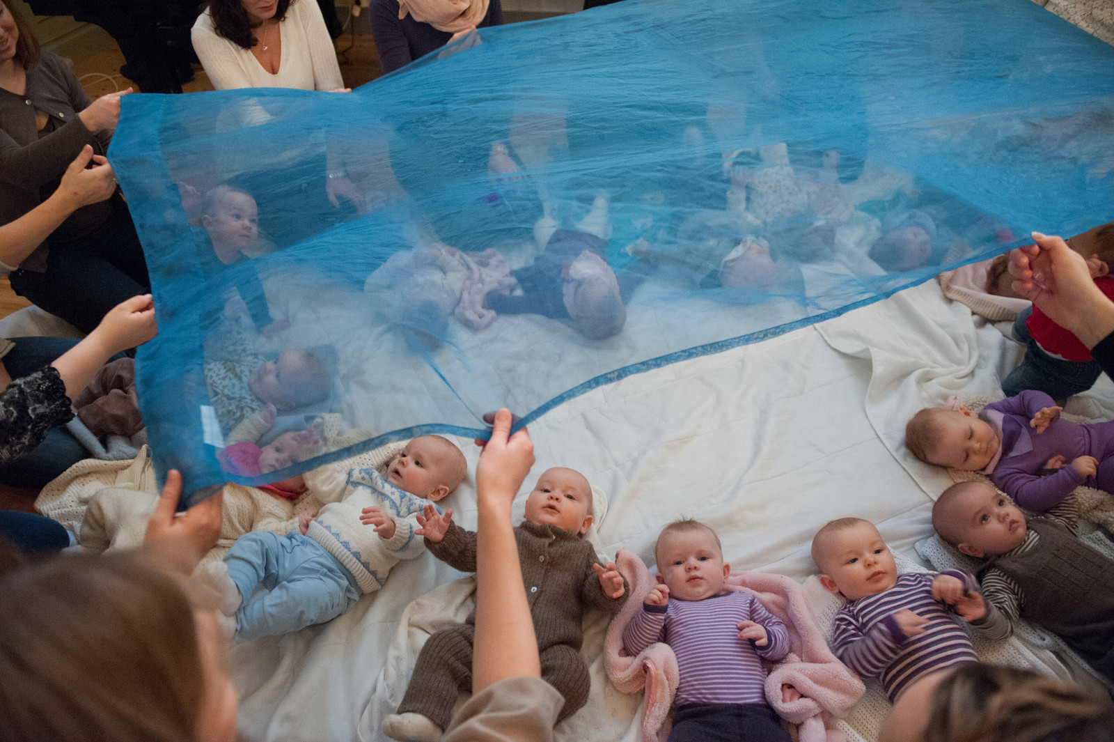 Mange babyer ligger på golvet under et gjennsiktig blått slør