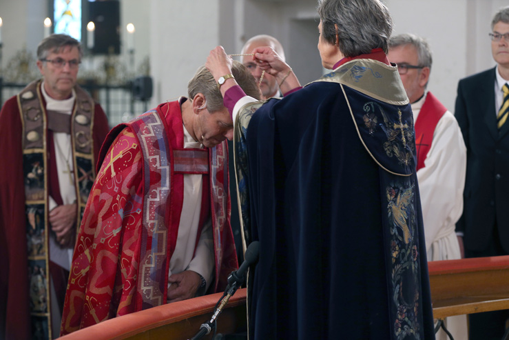 Bispemøtets preses Helga Haugland Byfuglien henger bispekorset om halsen på Tunsberg bispedømmes nye biskop, Per Arne Dahl